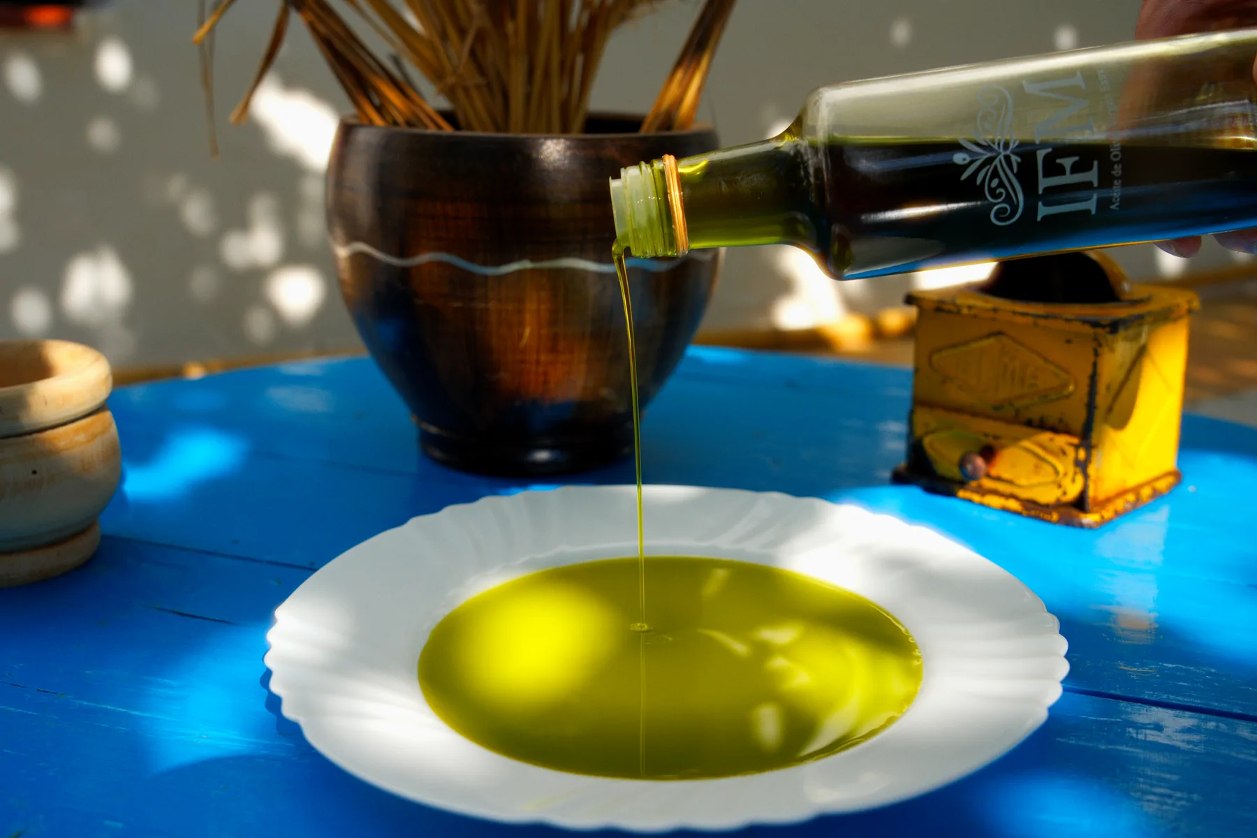 El aceite de IFM cae en un plato blanco sobre la mesa azul.